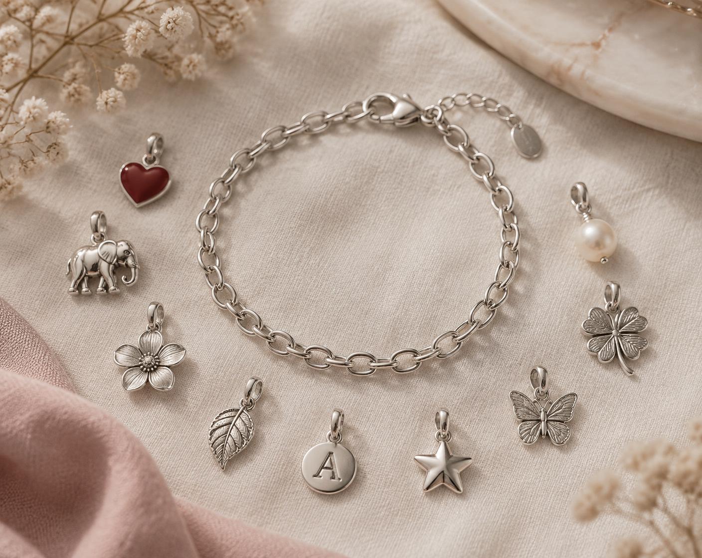 Silver chain charm bracelet surrounded by charms to choose from — heart, elephant, flower, leaf, initial, star, butterfly, clover and pearl